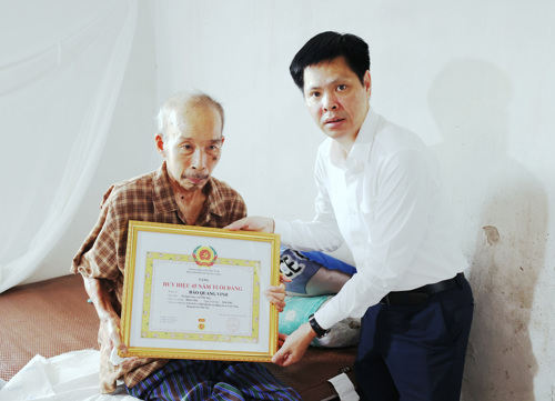 Đồng chí Nguyễn Tuấn Ngọc - Phó Bí thư Thường trực Đảng ủy xã Tam Nông trao Huy hiệu 45 năm tuổi Đảng cho đồng chí Đào Quang Vinh chi bộ 8 (Dân Quyền cũ)