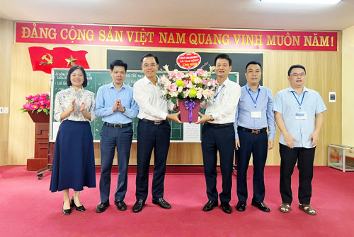Đồng chí Quách Hải Lý - Bí thư Đảng ủy, Chủ tịch HĐND xã tặng hoa chúc mừng Hội đồng thi tại THPT Hưng Hóa xã Tam Nông